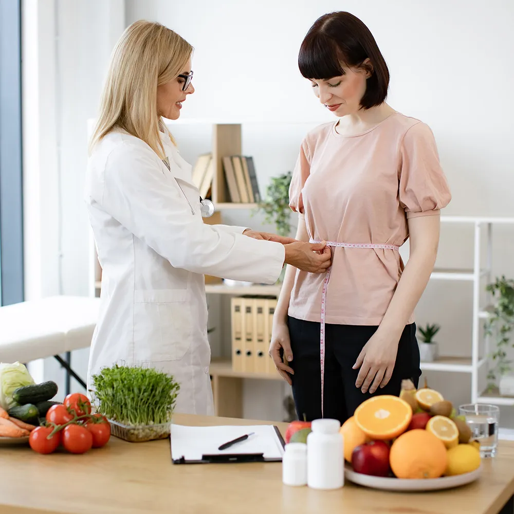 A doctor measuring a patient's waist during a nutrition consultation.