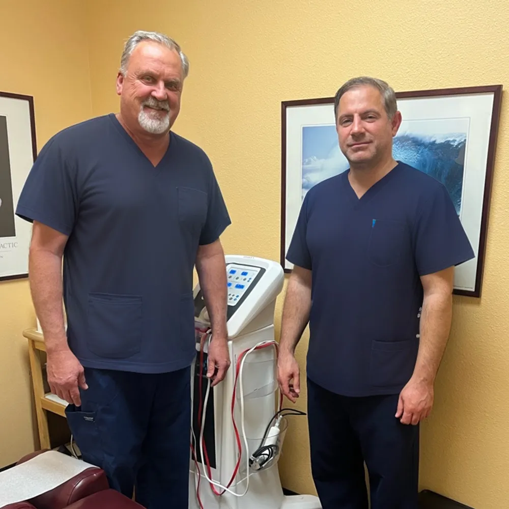 Two chiropractors standing beside therapy machine