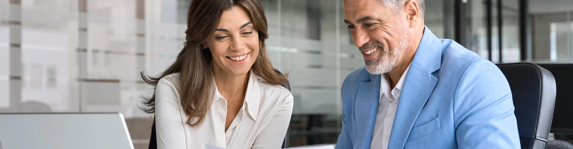 Man and woman smiling while looking at laptop.