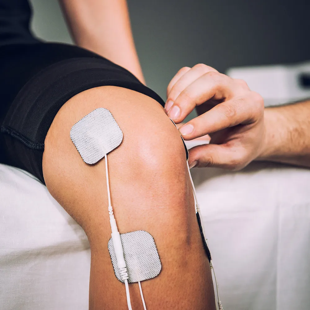 Man applying electrical therapy to knee
