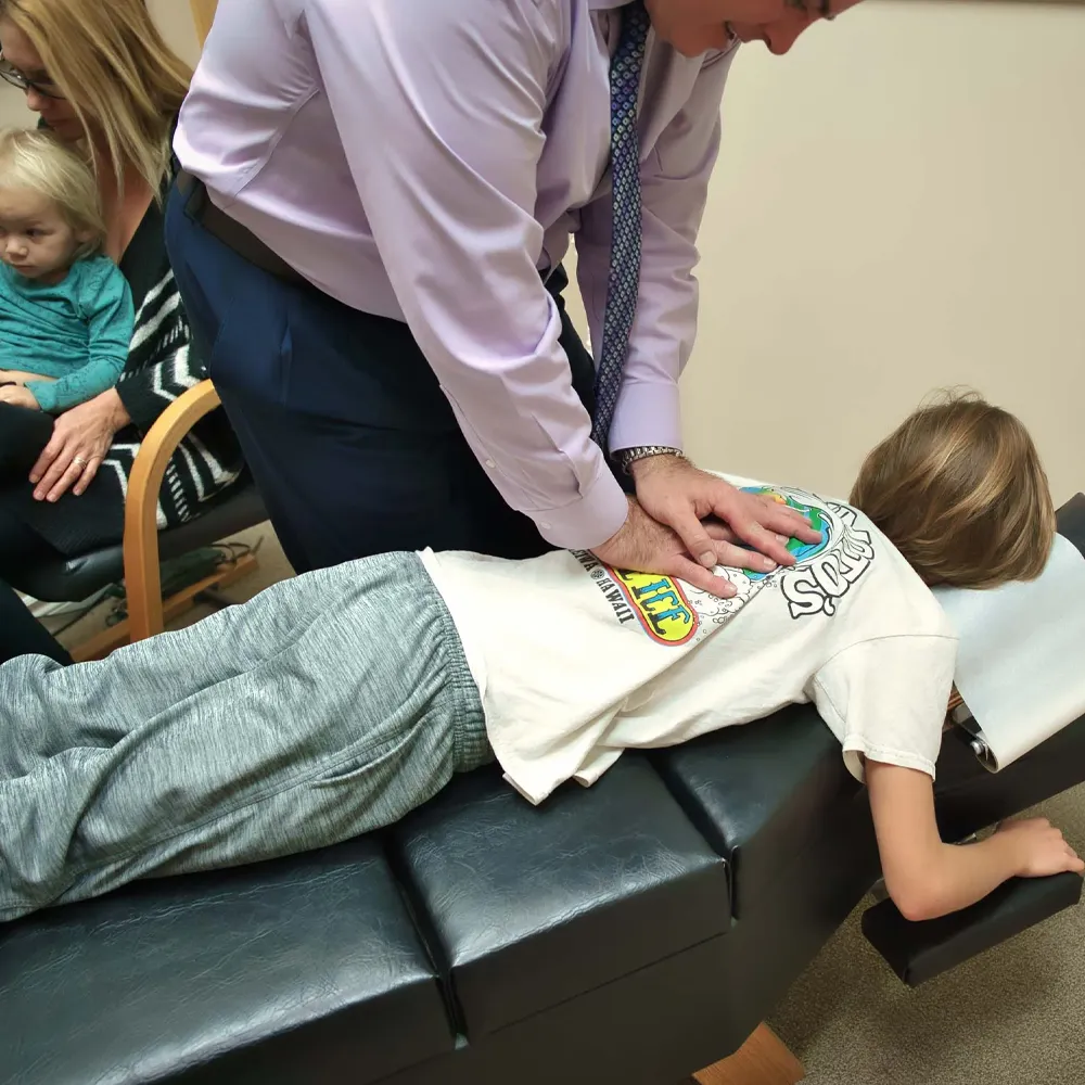 Chiropractor adjusting child with parent nearby