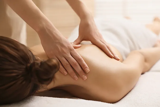 Therapist performing back massage on woman.