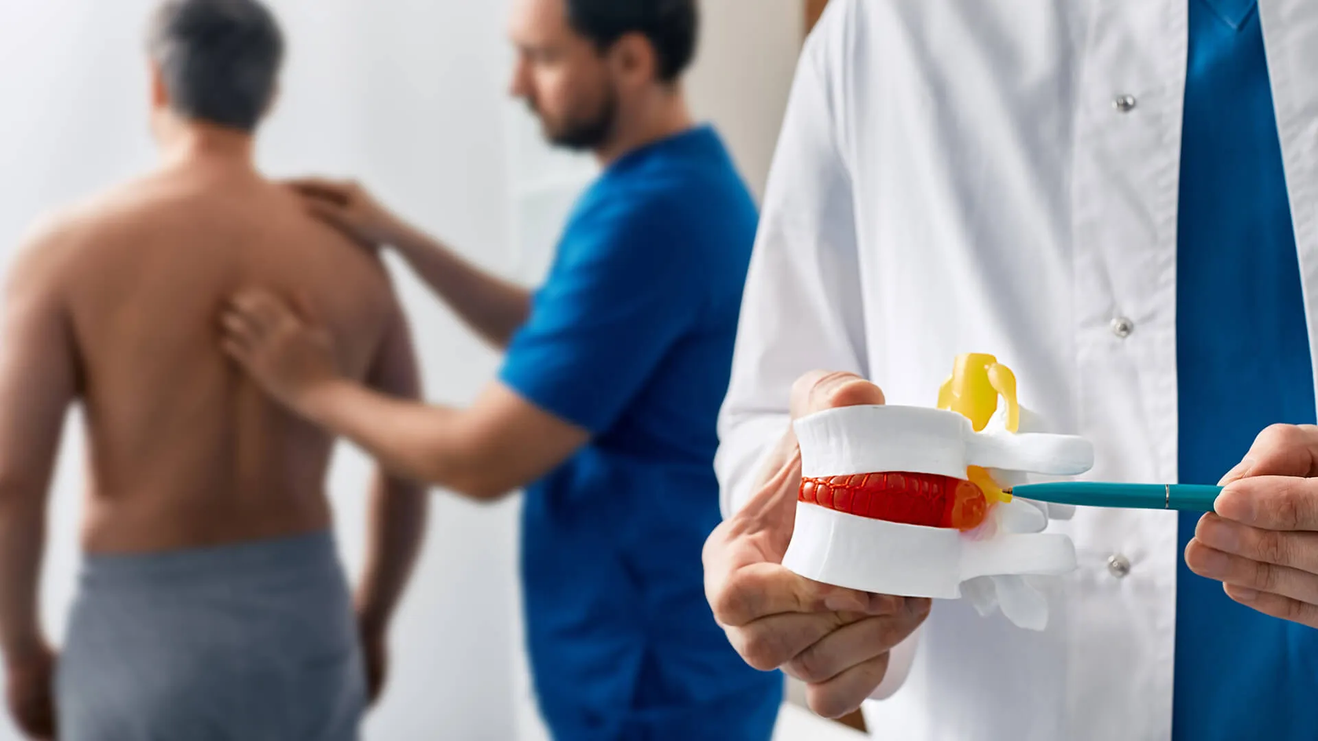 Doctor explaining herniated disc injuries with spine model.
