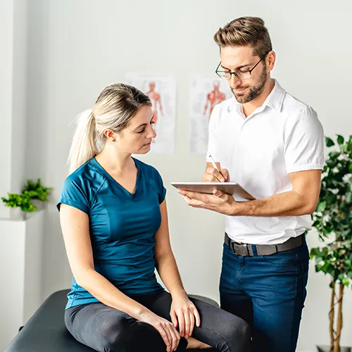 Chiropractor showing information to patient on a tablet in treatment room.