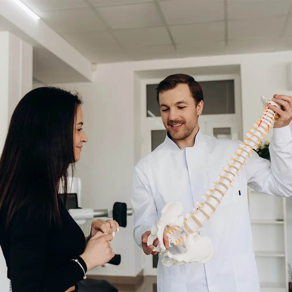Chiropractor explaining scoliosis with spine model.