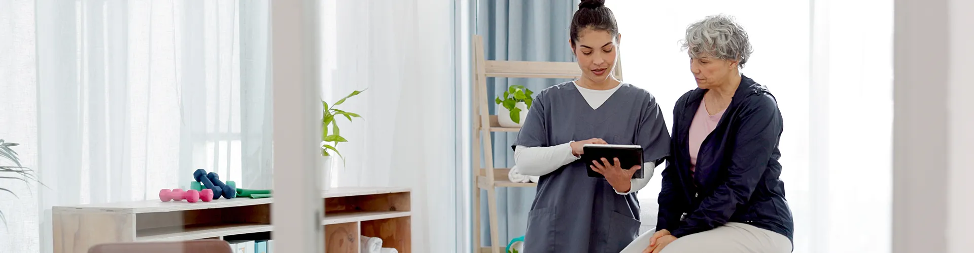 Chiropractor showing information to patient on a tablet in treatment room.
