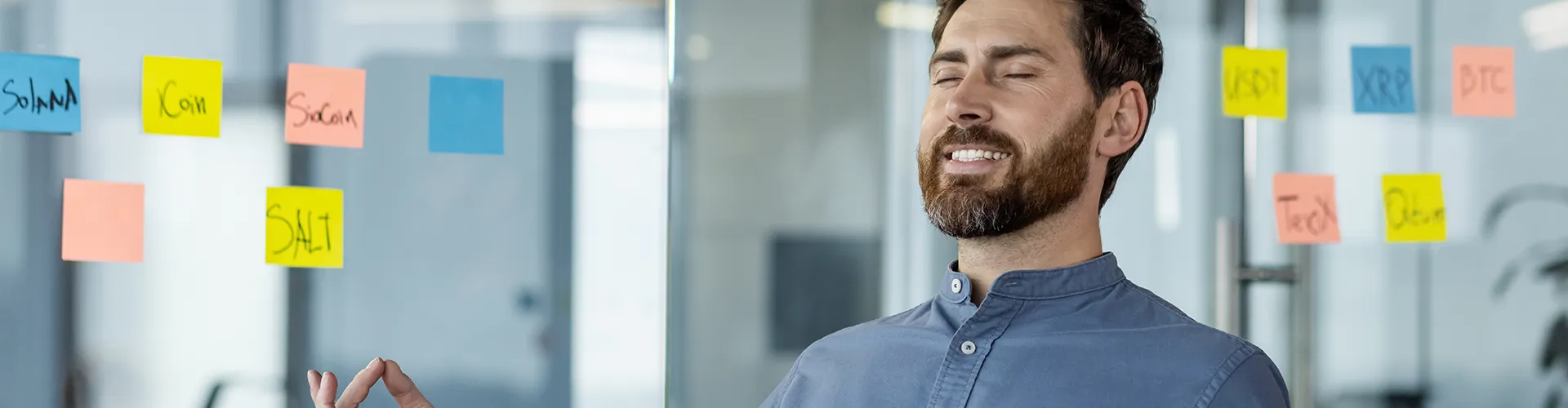 Man in office smiling with closed eyes, sitting in gyan mudra pose.
