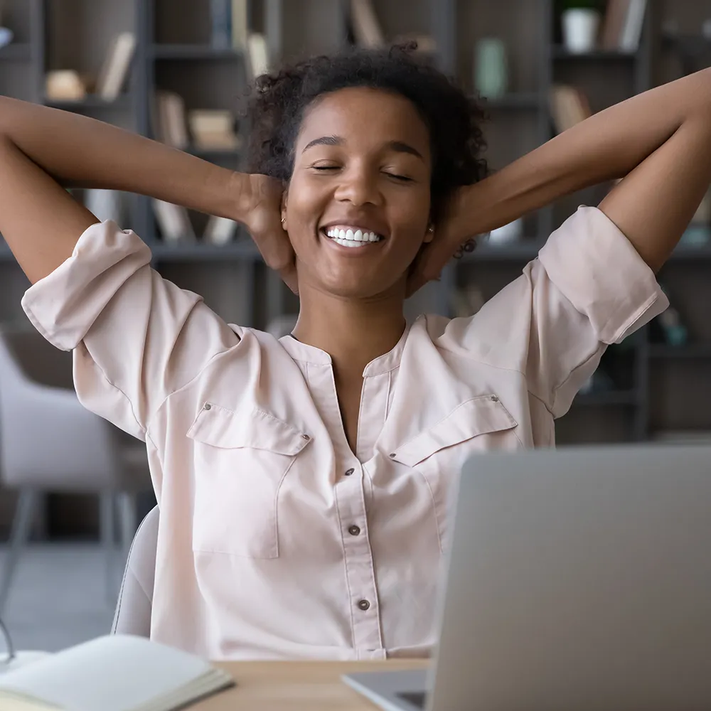 Smiling woman stretching back with hands raised.