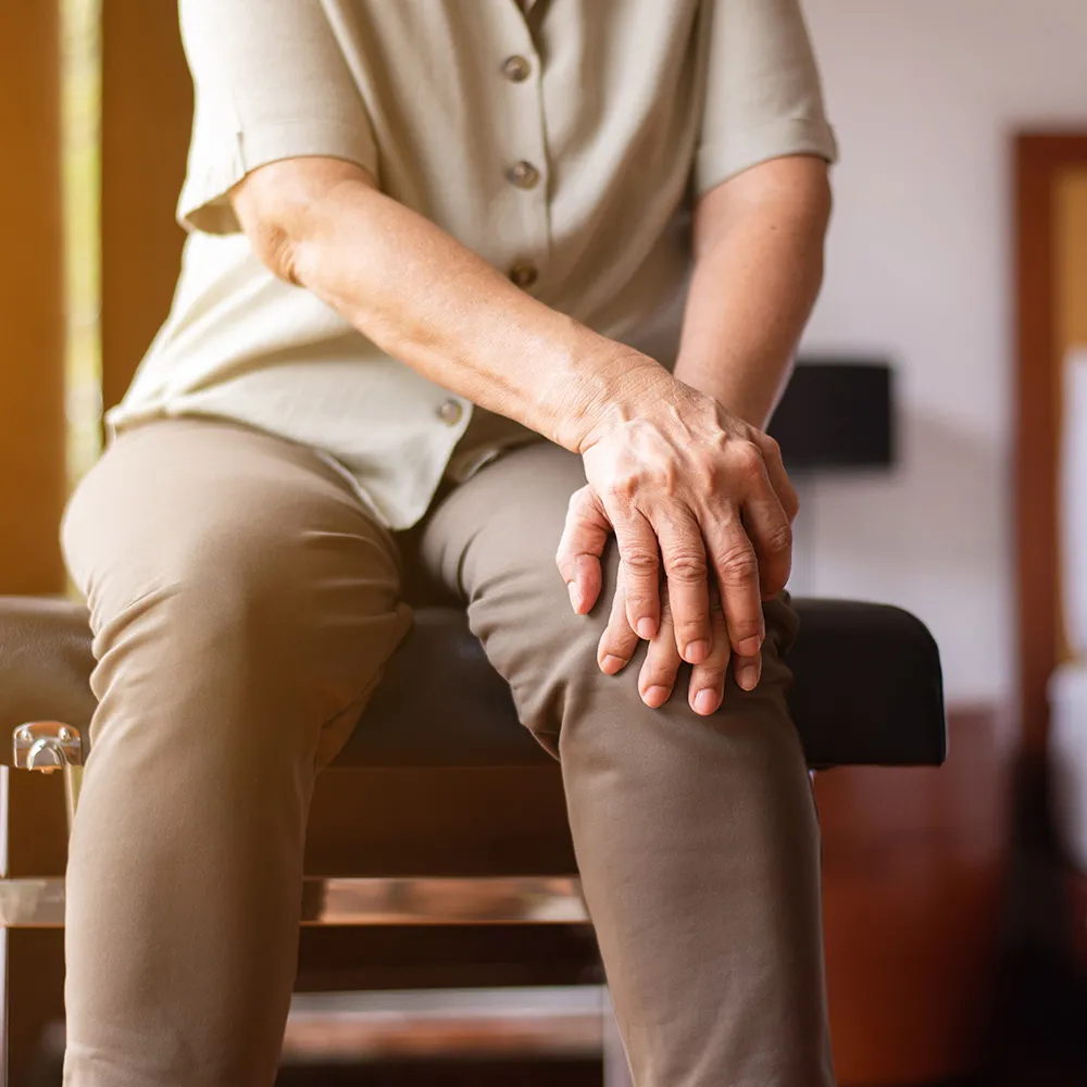 Older person holding a knee in pain.