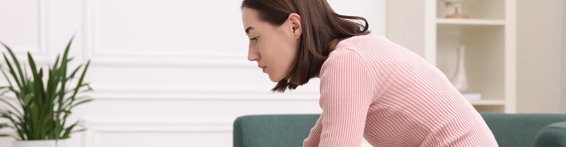 Woman seated, leaning forward while using a laptop.