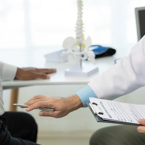 Chiropractor taking notes with pen about patient’s condition.