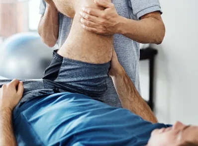 Chiropractor evaluating patient’s knee on therapy table  