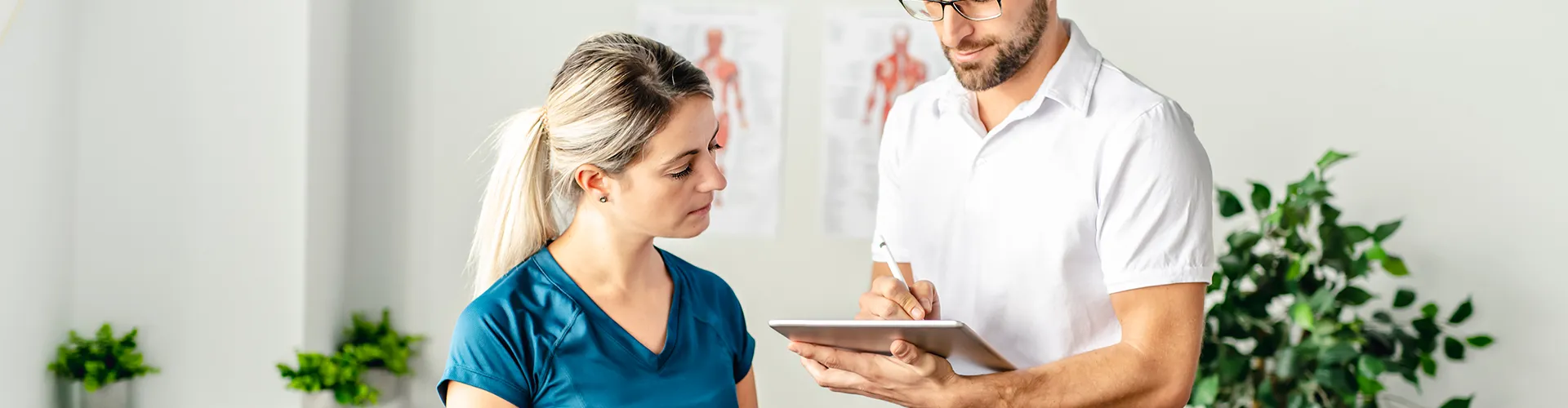 Chiropractor showing information to patient on a tablet in treatment room.