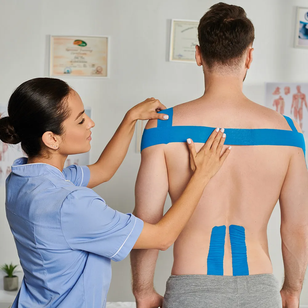 Therapist applying kinesio tape to patient’s shoulder