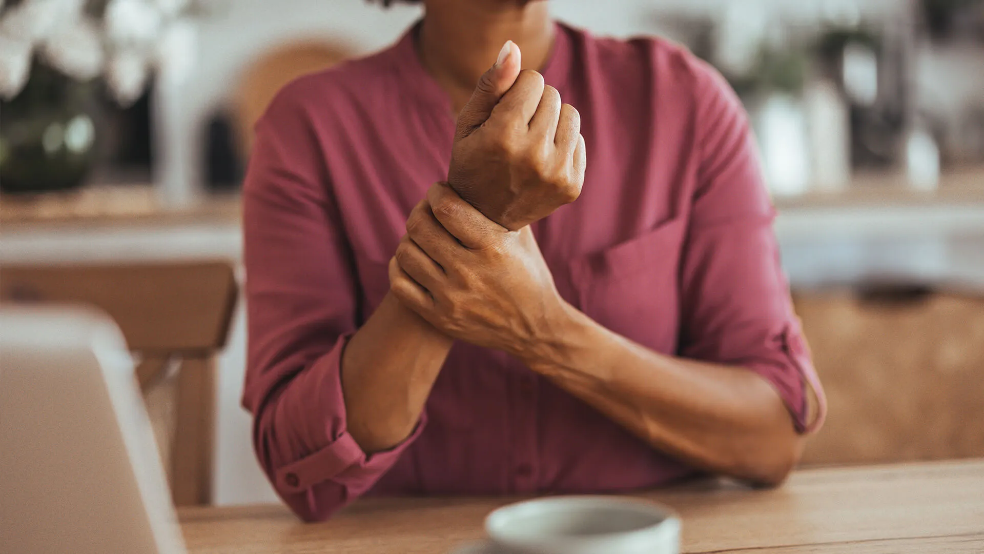 Person in pink shirt holding painful wrist.