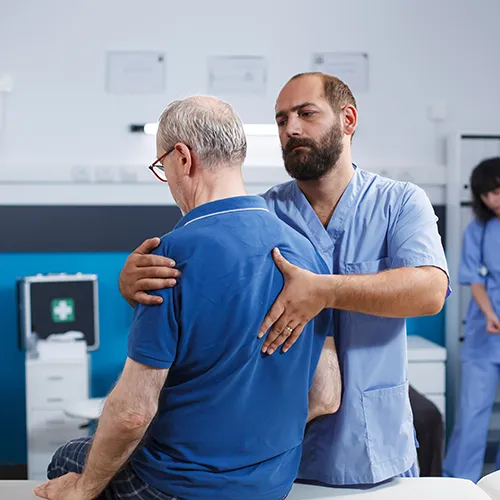 Chiropractor adjusting seated patient’s back.