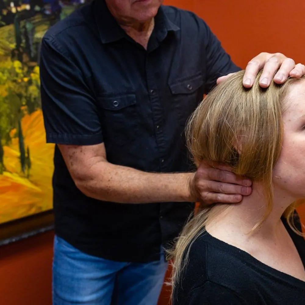 Chiropractor adjusting patient’s neck by hand
