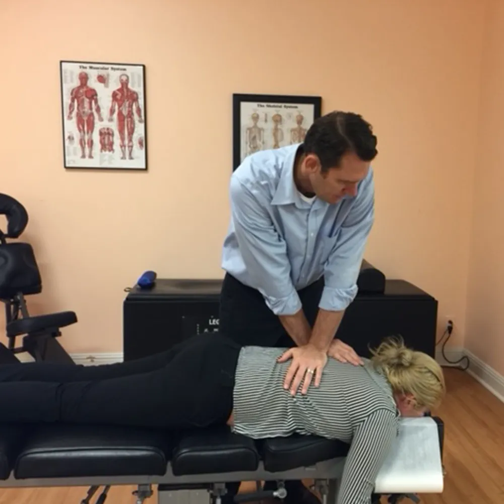 Chiropractor adjusting woman’s spine on treatment table.