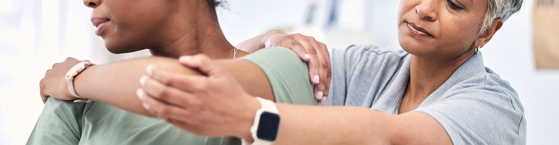 Chiropractor examining woman’s shoulder.