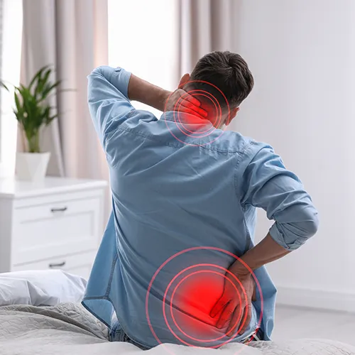 Patient seated on edge of bed holding back in discomfort.