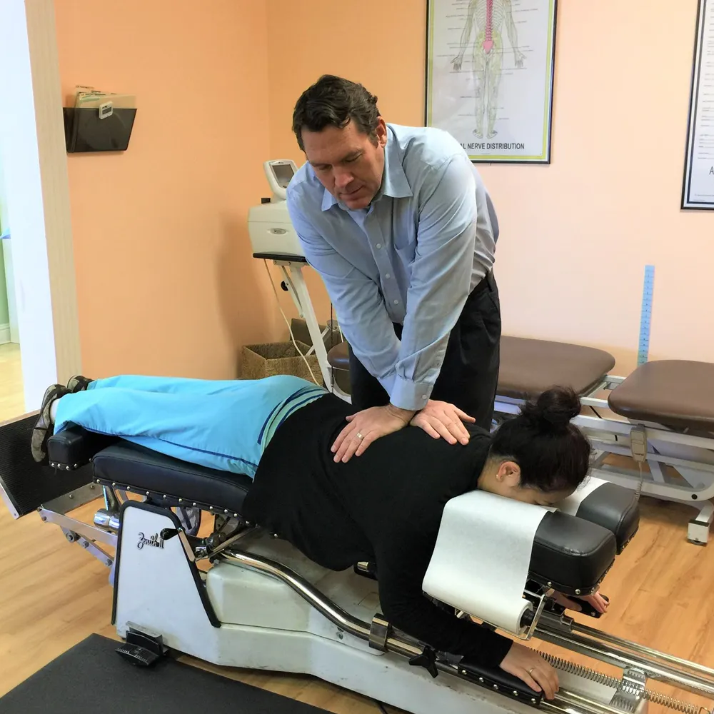 Chiropractor performing spinal adjustment on patient.