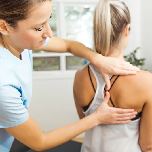 Chiropractor examining patient’s upper back near shoulder blade.