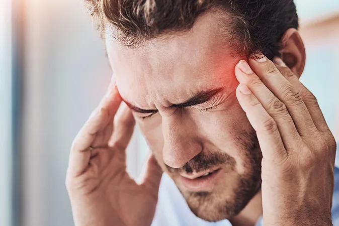  A man holding his temples, with a glowing red area symbolizing a headache.