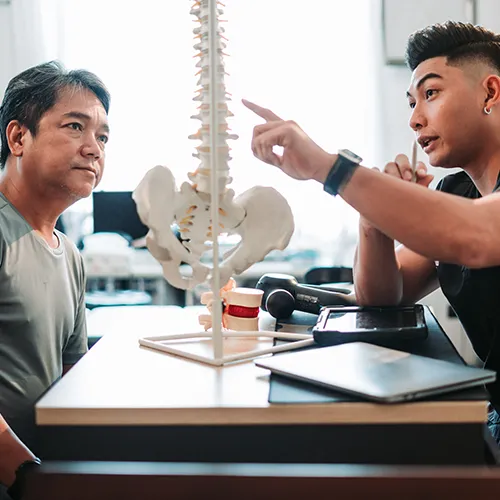 Chiropractor using spine model to explain treatment to patient.