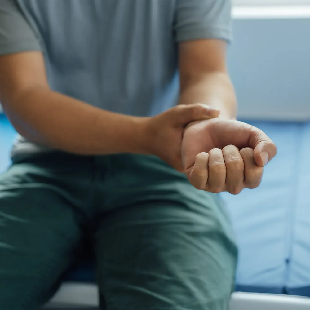 Man in blue shirt holding sore wrist.
