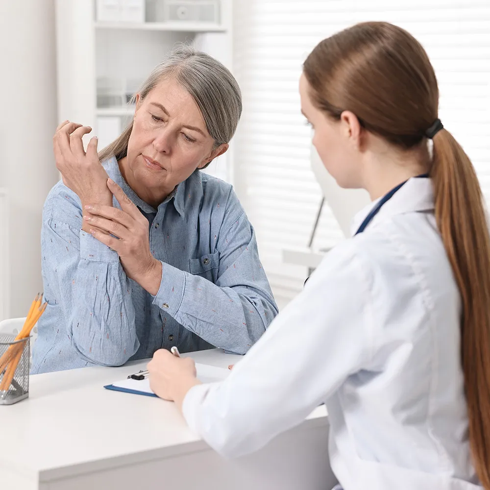 Older woman showing wrist pain to doctor.