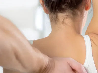 Chiropractor examining patient’s upper back and shoulder.