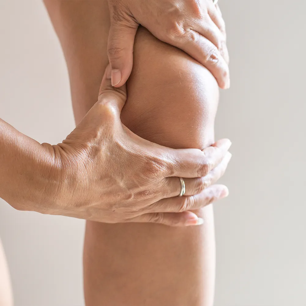 Close-up of hands gripping a painful knee.