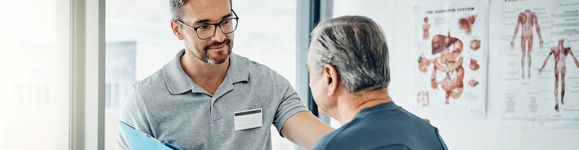 Chiropractor placing hand on seated patient’s shoulder while explaining treatment.
