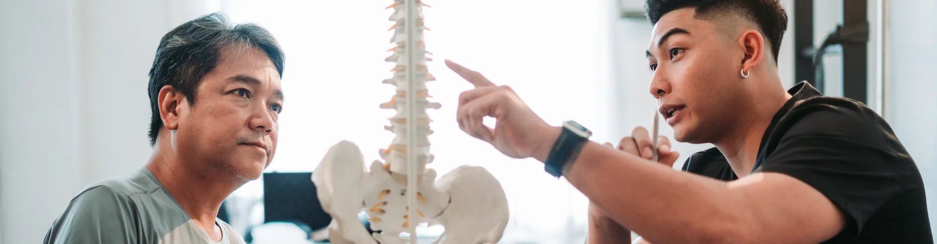 Chiropractor using spine model to explain treatment to patient.