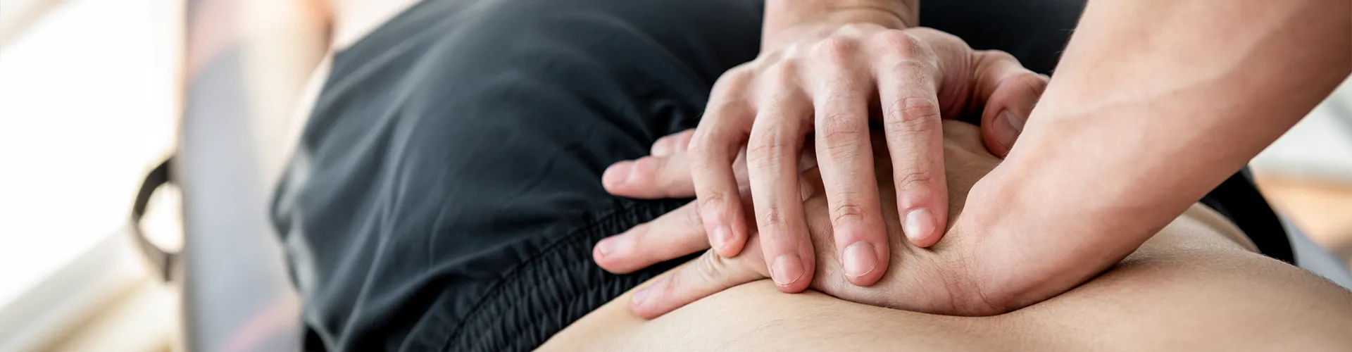 Hands applying pressure to patient’s lower back.