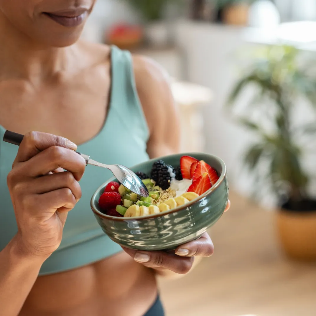 Woman eating a bowl of fruit.