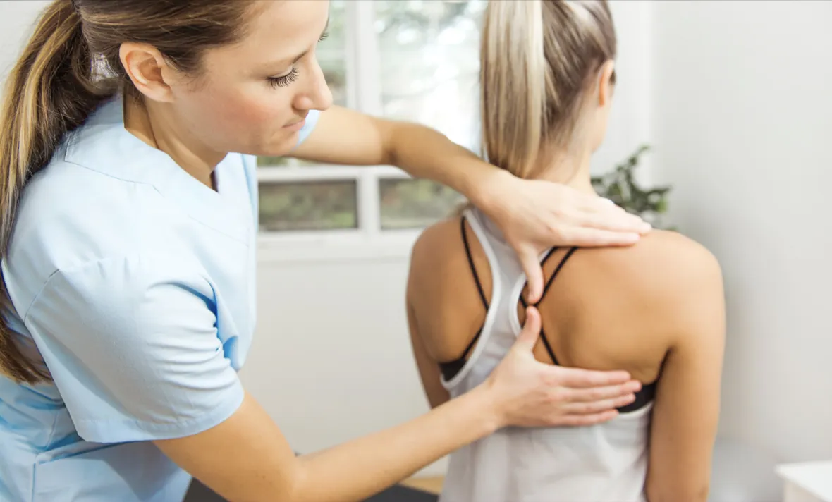 Chiropractor examining patient’s upper back near shoulder  