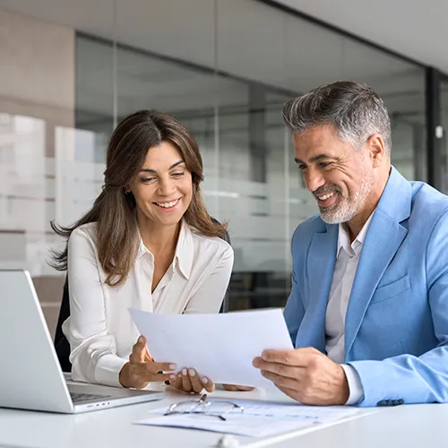 Man and woman smiling while looking at laptop.