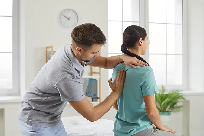 Osteopath examining woman’s upper back  